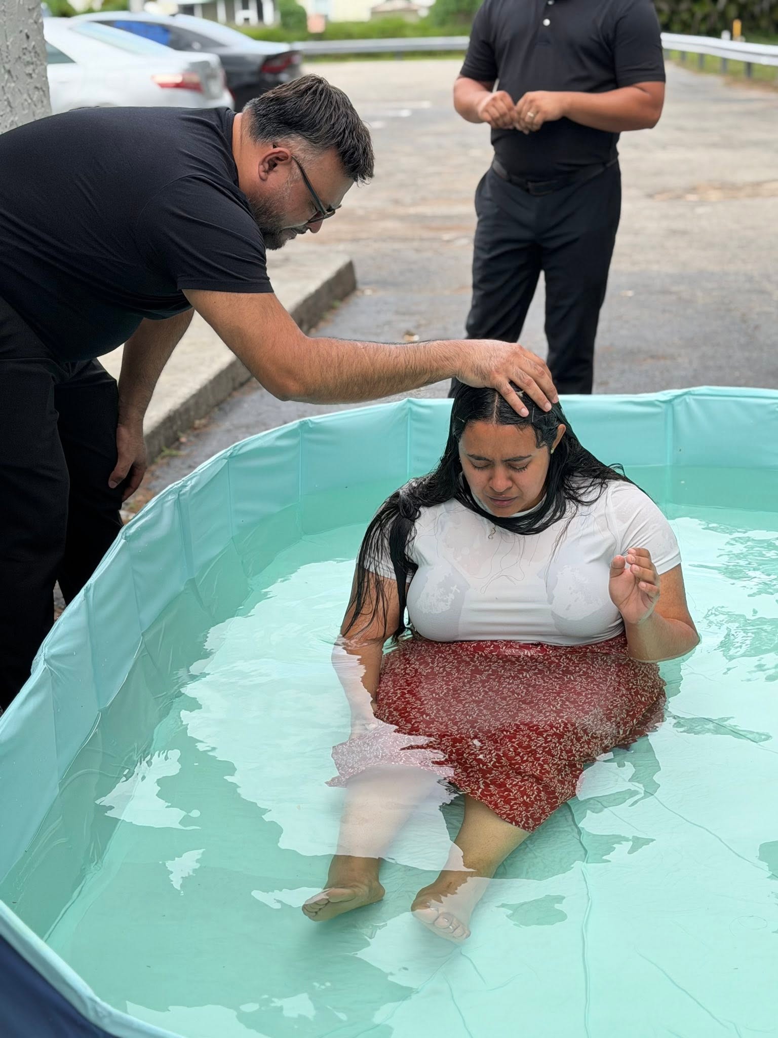 Una persona siendo bautizada, acompañada por miembros de la iglesia